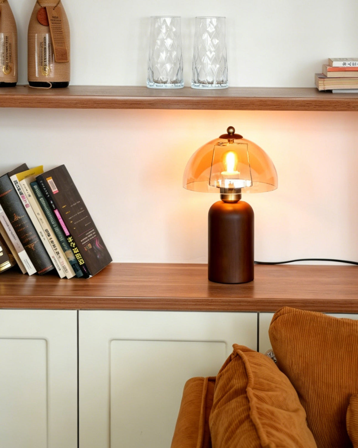 Lámpara de mesa de madera y cristal ámbar Rubana – encendida en una estantería junto al sofá