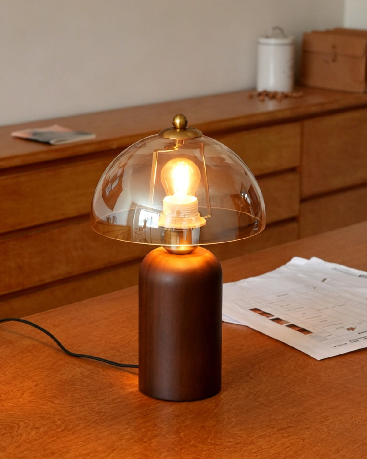 Lámpara de mesa de madera y cristal ámbar Rubana – encendida sobre un mueble de madera