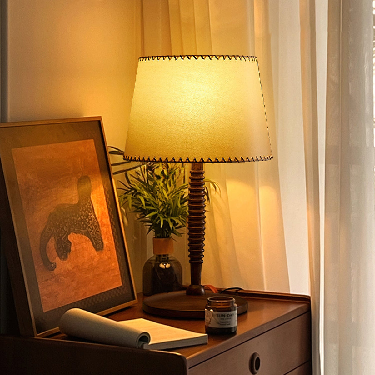 Lámpara de mesa de madera torneada Rueca – en un escritorio con cuadro