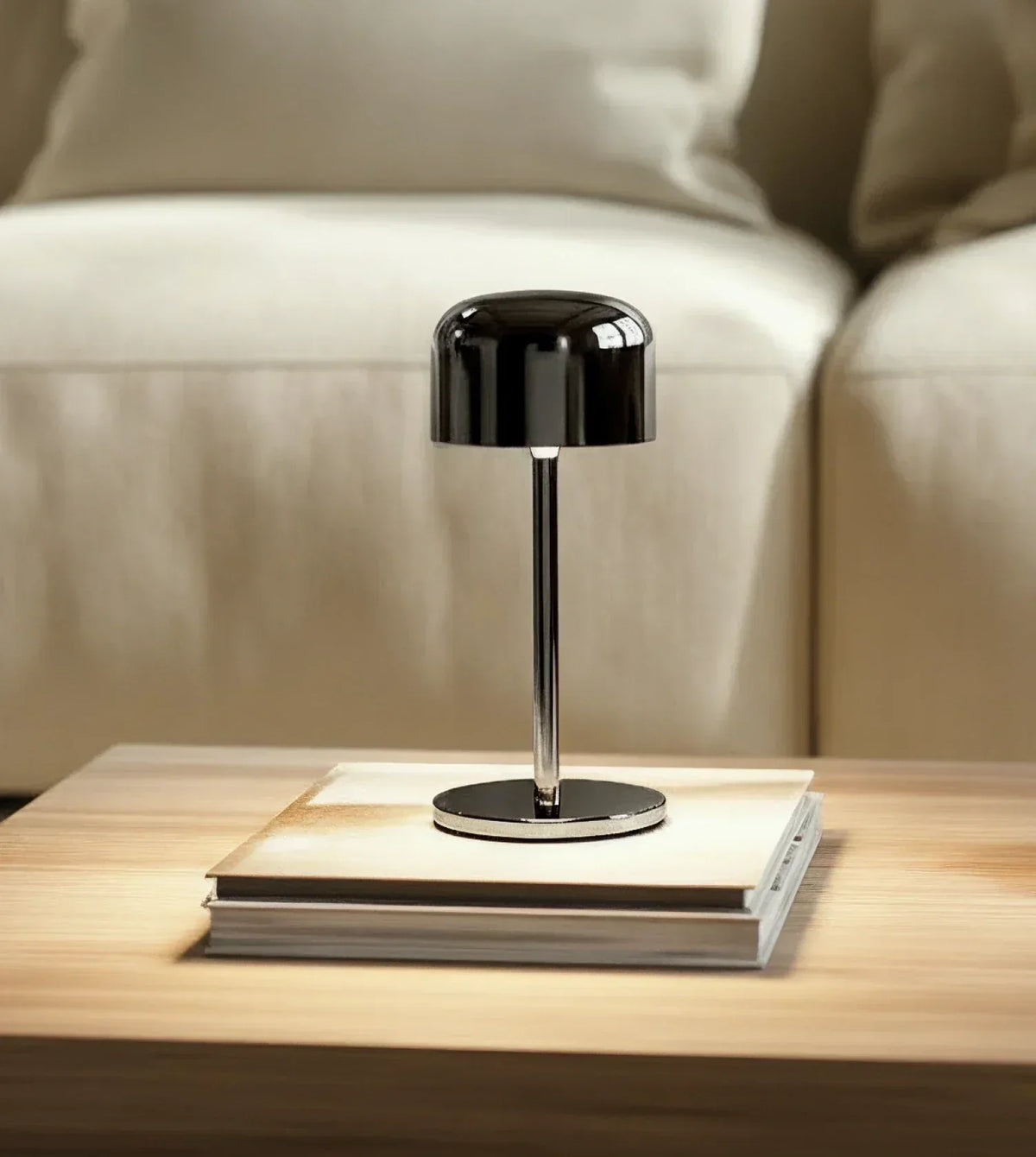 Lámpara de mesa recargable Rupela – en negro cromado sobre una mesa de centro