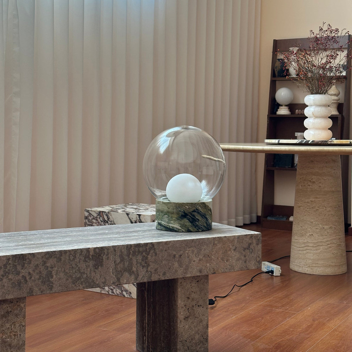 Lámpara de mesa de cristal Saquira – sobre un banco de travertino