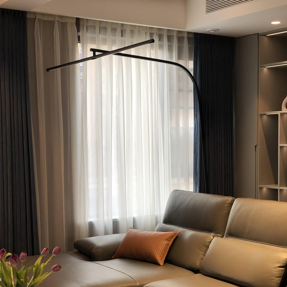 Lámpara de pie de arco LED Sigela – sobre un sofá de piel en penumbra