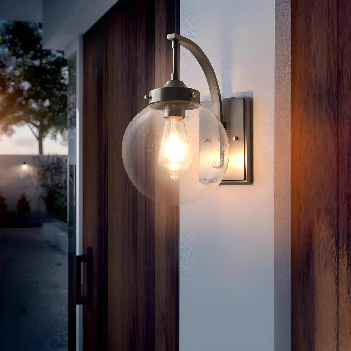 Aplique de pared exterior Ozela – junto a una puerta de madera al anochecer