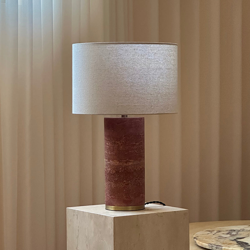 Lámpara de mesa de piedra Sivana – encendida sobre un pedestal de travertino