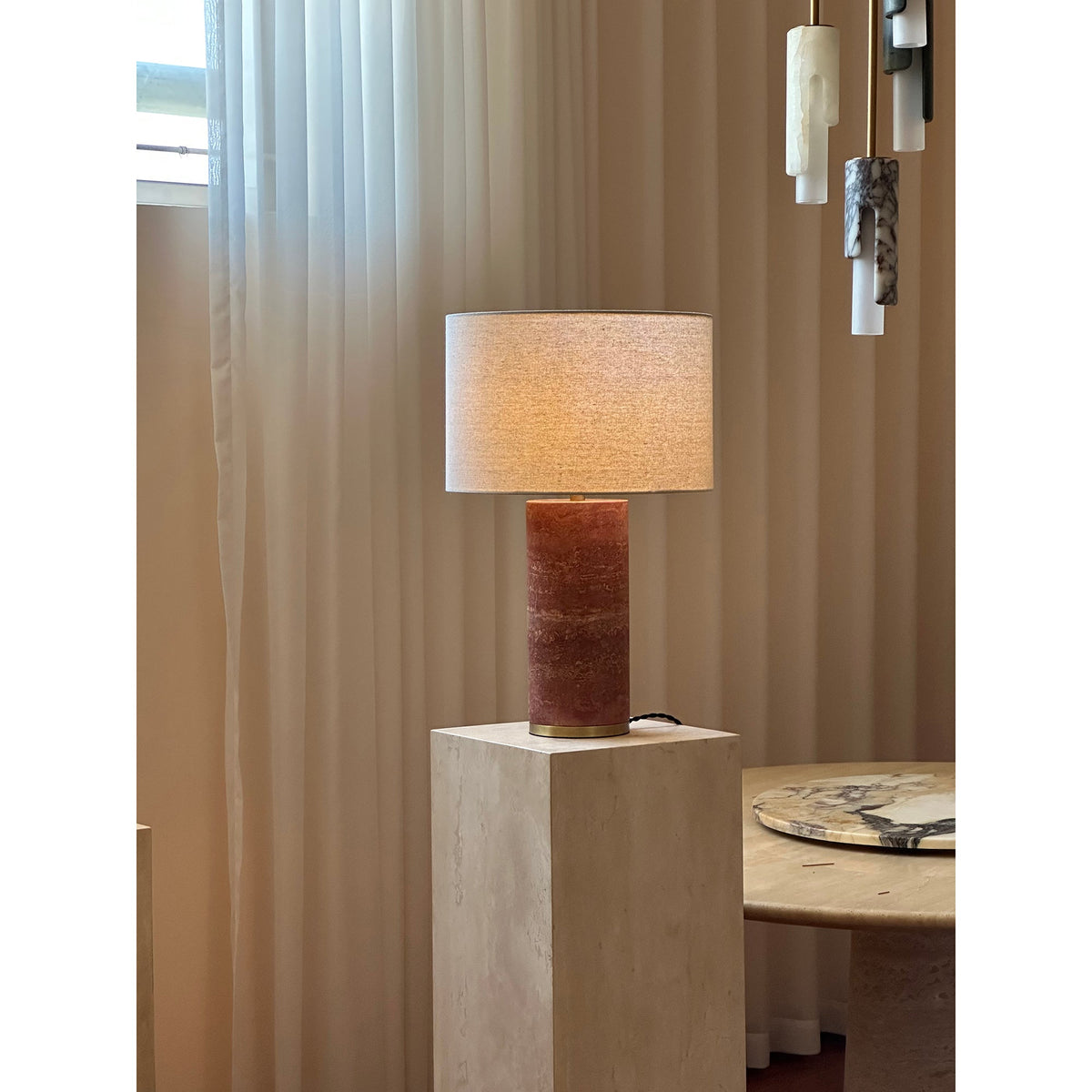 Lámpara de mesa de piedra Sivana – travertino rojo junto a una ventana