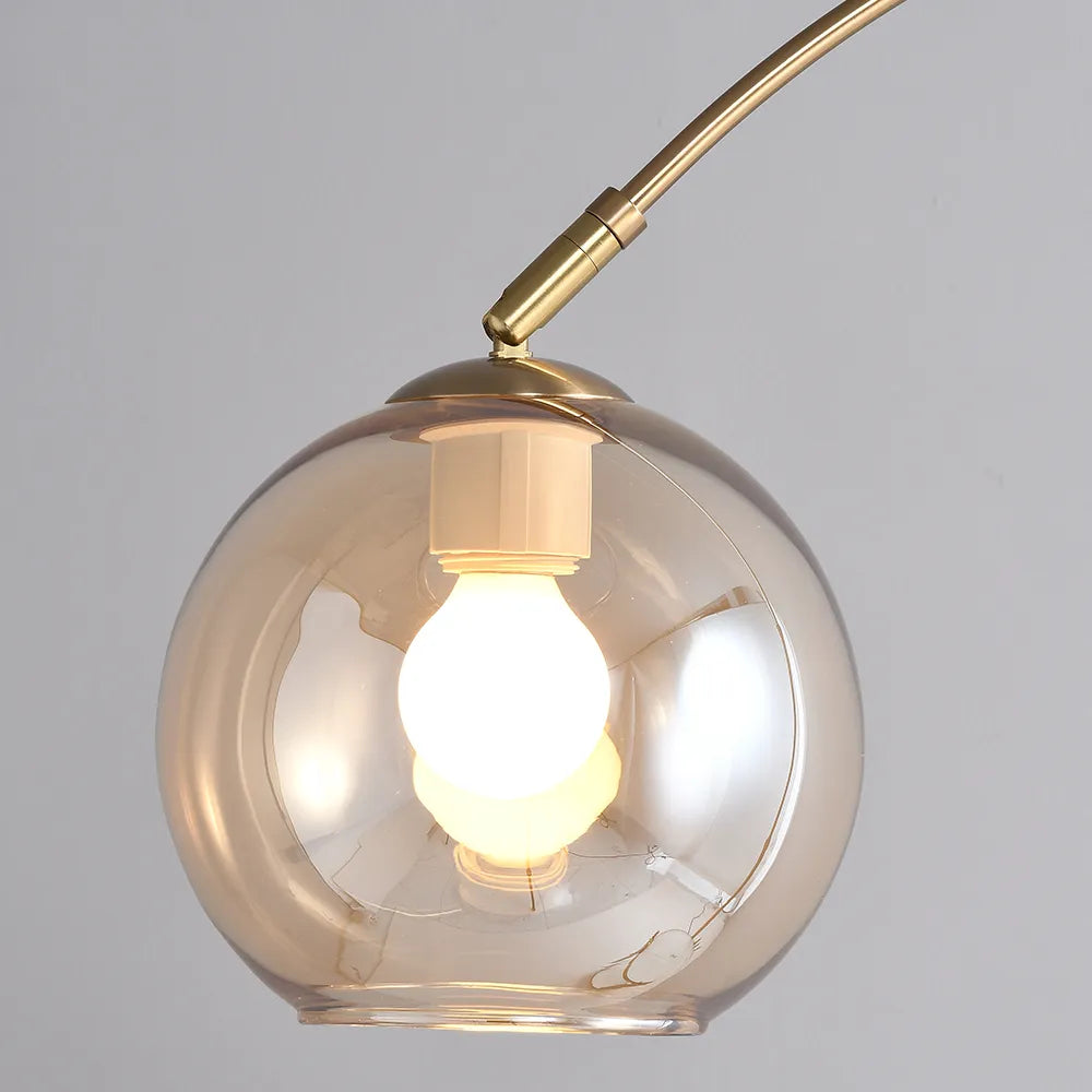 Lámpara de pie arco dorada Solmesa con mesa auxiliar – globo de cristal ámbar encendido