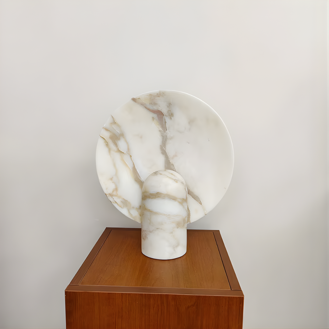 Lámpara de mesa de piedra Solsticia – en mármol claro sobre un mueble de madera