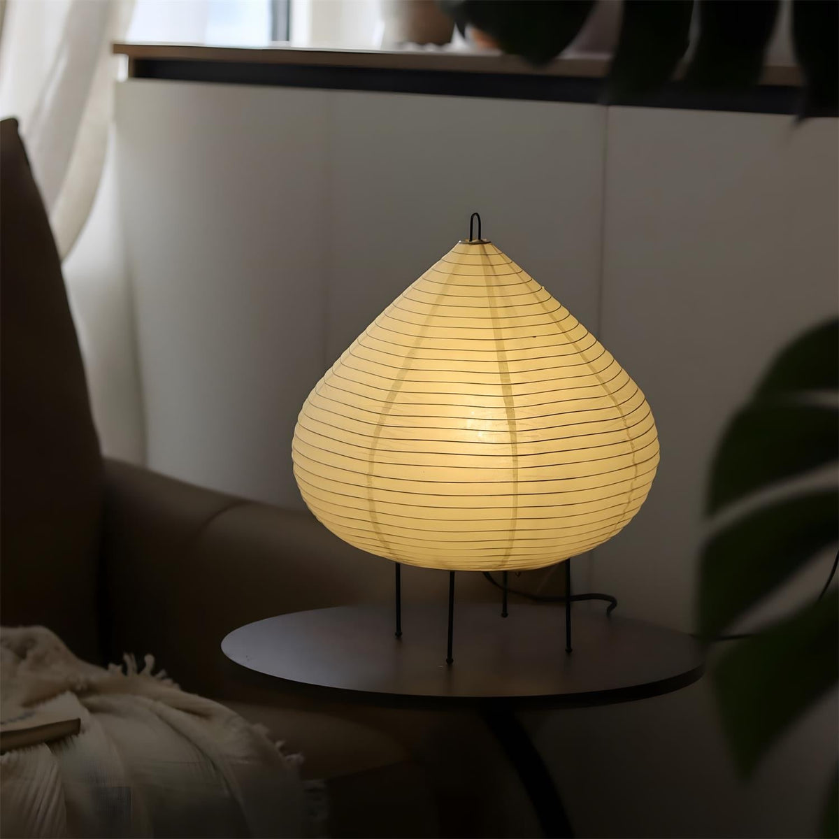 Lámpara de mesa de papel Sutila – encendida junto a un sillón