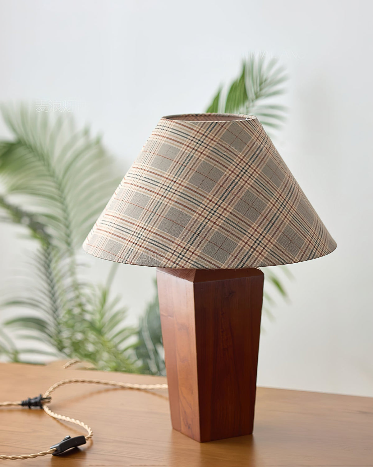 Lámpara de mesa de nogal Tartela – junto a una planta
