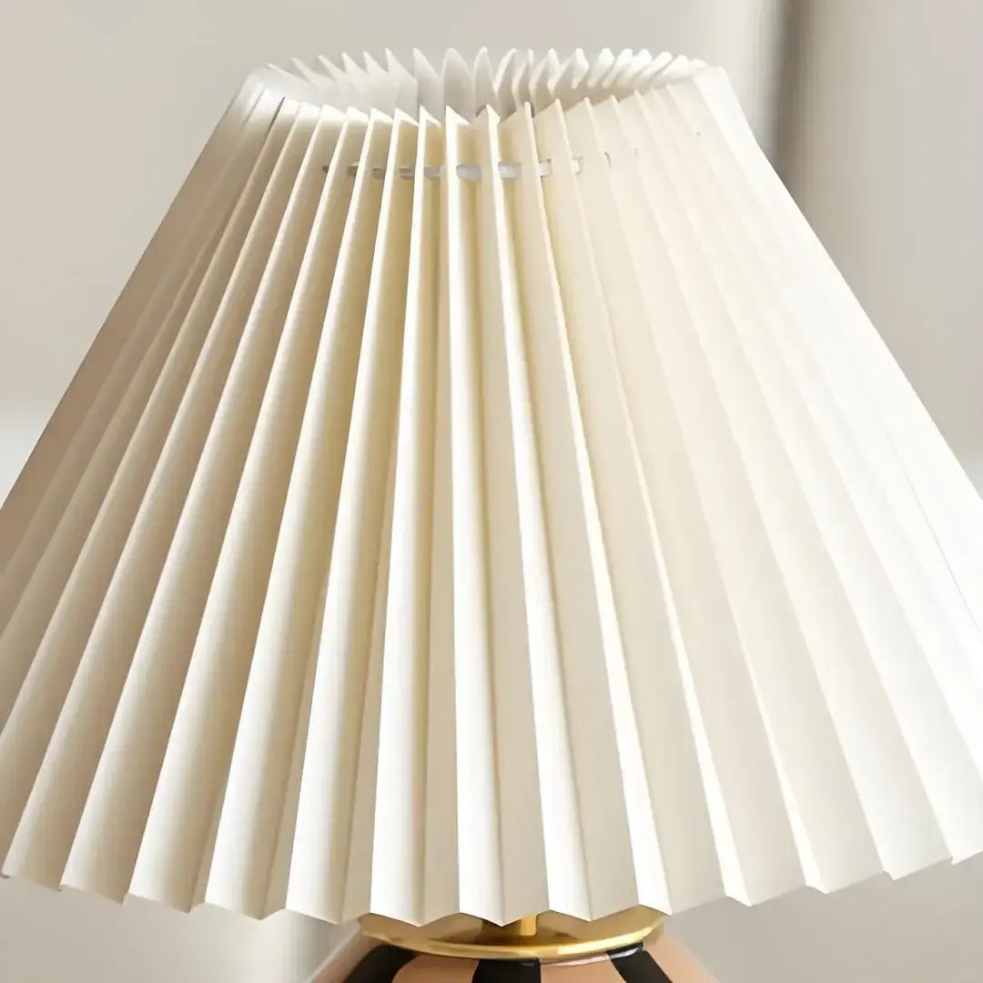 Lámpara de mesa de vidrio con pantalla plisada Tesira sobre una mesa de madera – imagen 11