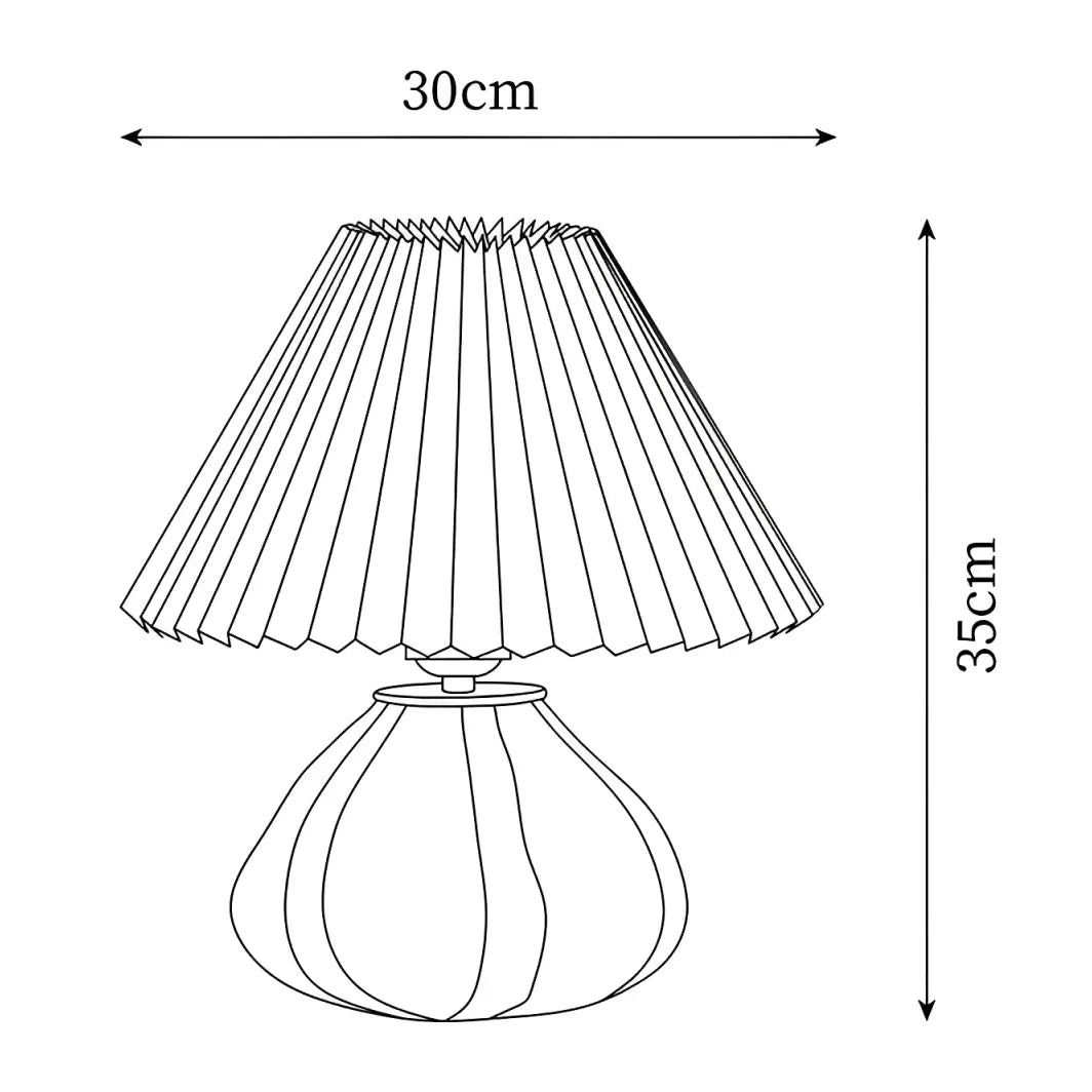 Lámpara de mesa de vidrio con pantalla plisada Tesira sobre una mesa de madera – imagen 14
