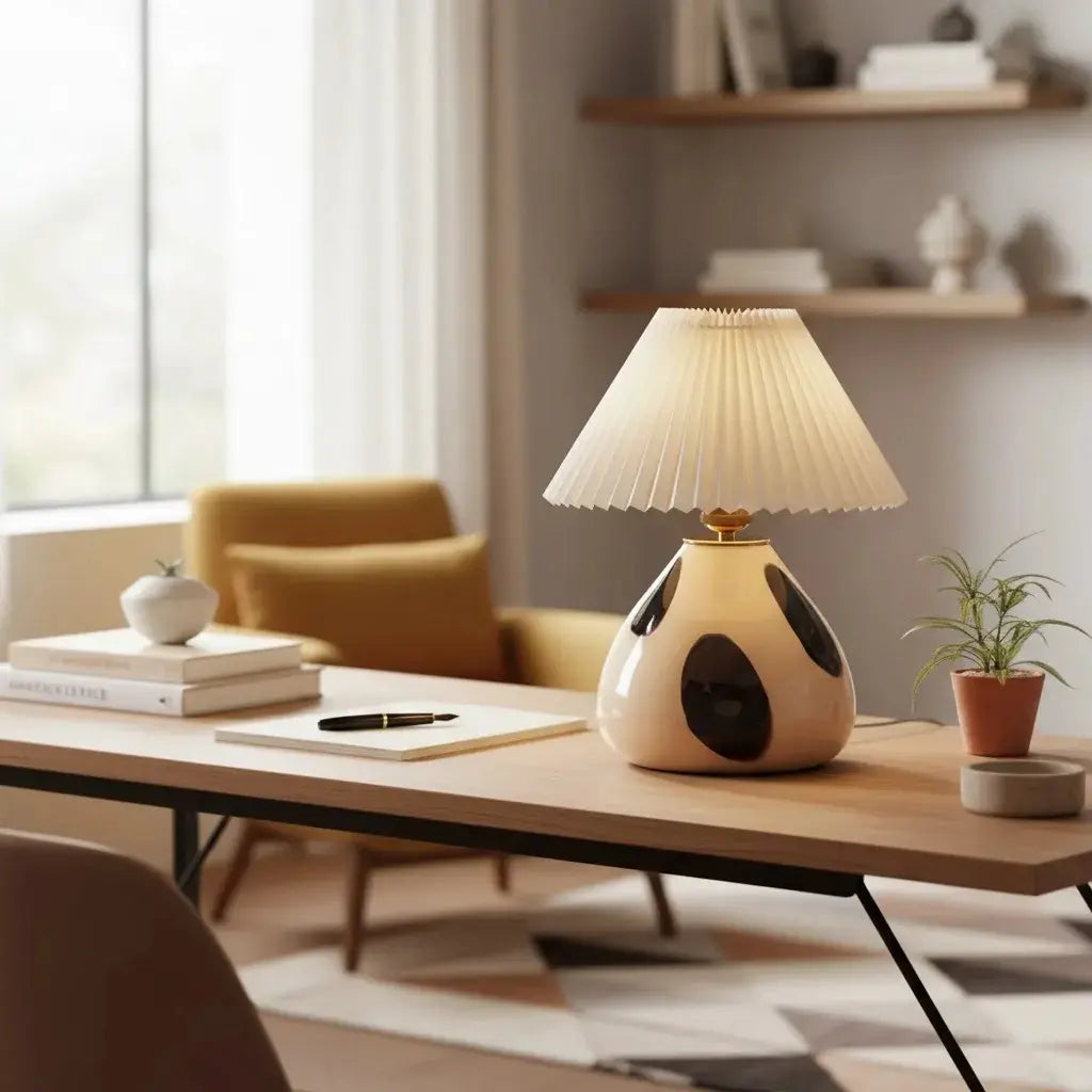 Lámpara de mesa de vidrio con pantalla plisada Tesira sobre una mesa de madera – imagen 4