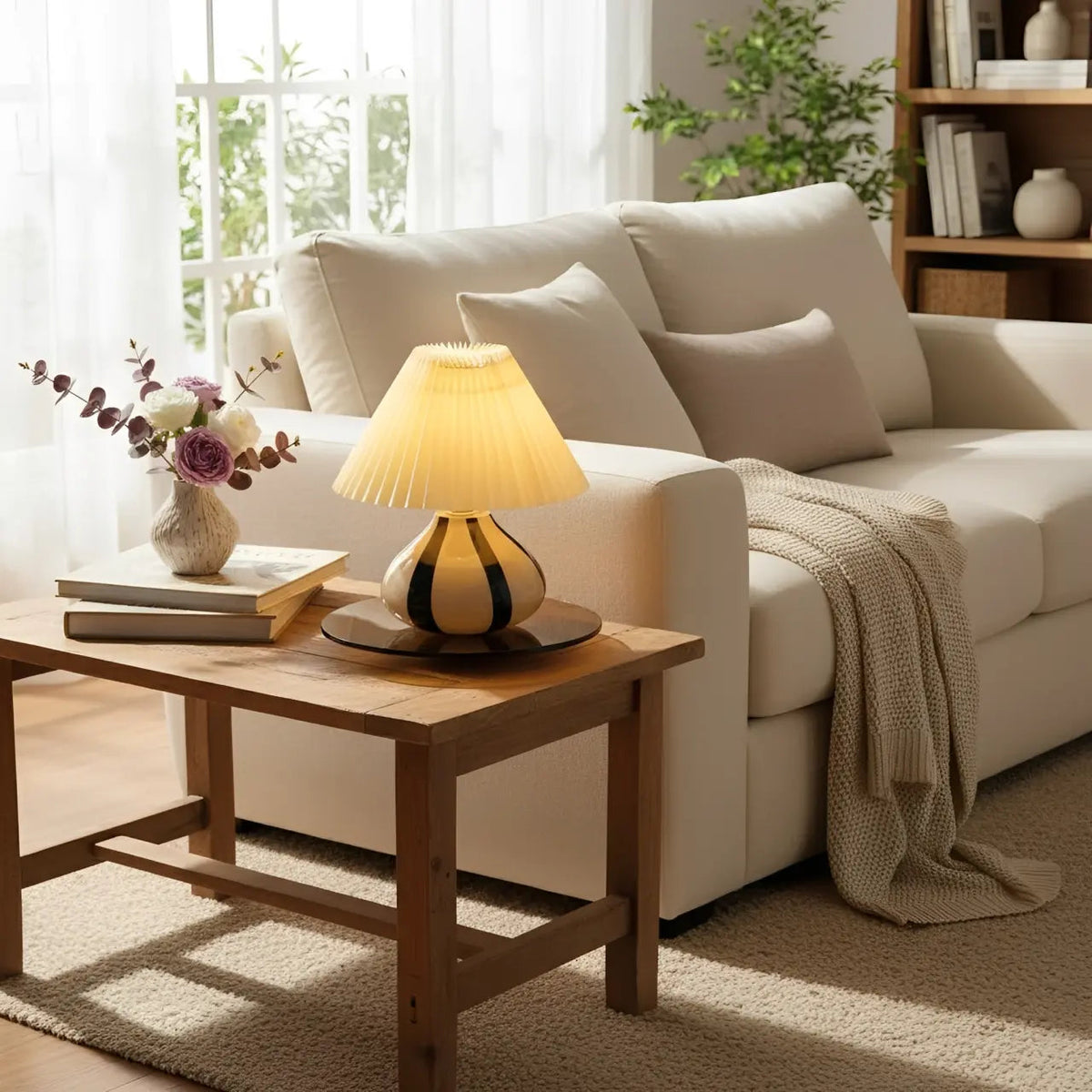 Lámpara de mesa de vidrio con pantalla plisada Tesira sobre una mesa de madera – imagen 6