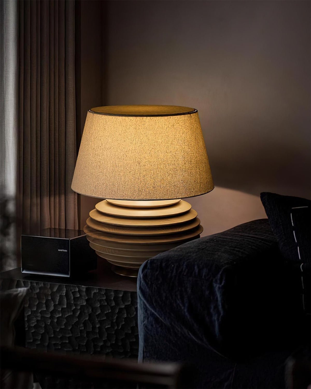 Lámpara de mesa de madera Torneda – encendida en un salón oscuro