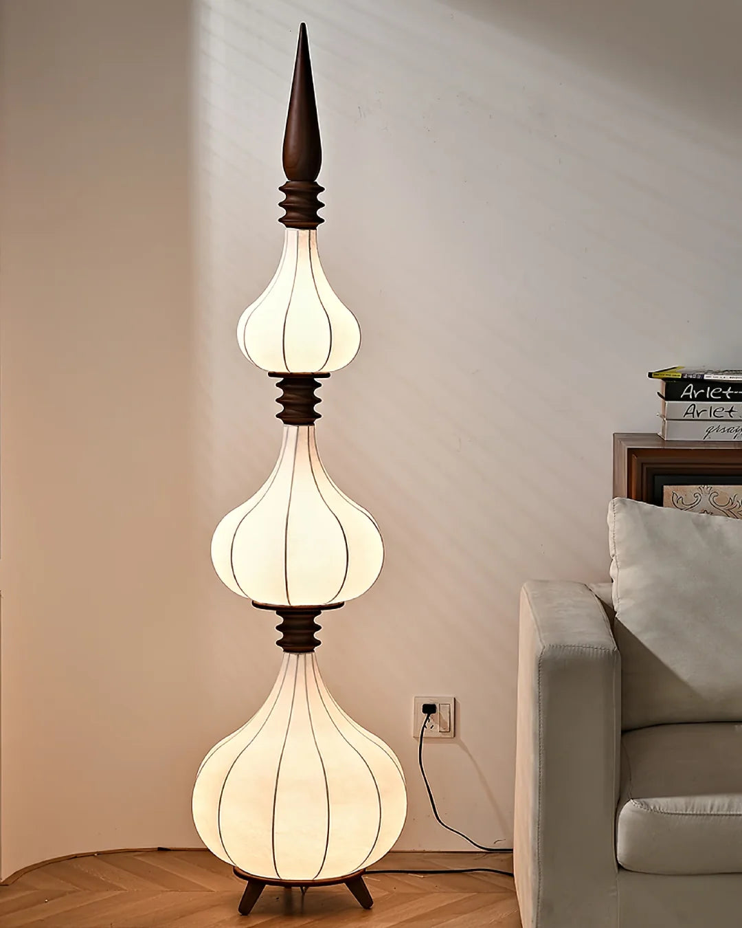 Lámpara de pie de tela y madera Torrina – de tres globos junto a un sillón gris
