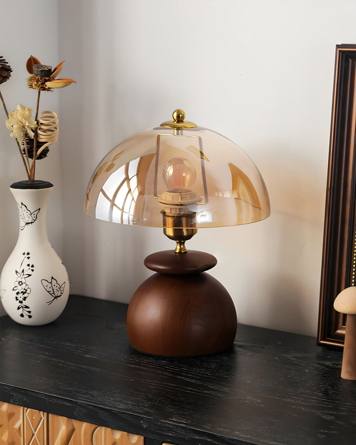 Lámpara de mesita de madera Tostana – sobre una cómoda junto a un cuadro