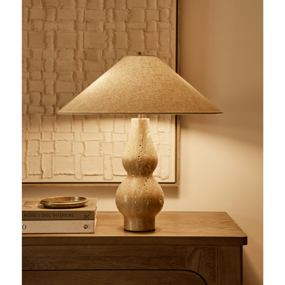 Lámpara de mesa de travertino Travia – encendida sobre una cómoda de madera