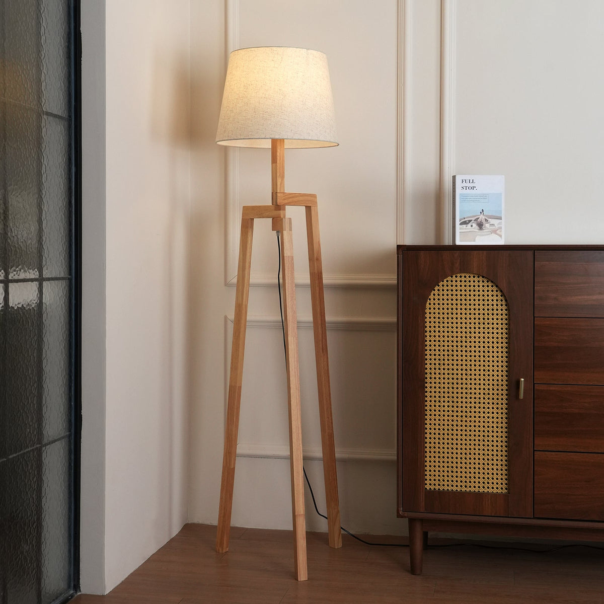 Lámpara de pie trípode de madera Tresalba – junto a un aparador de madera y rejilla