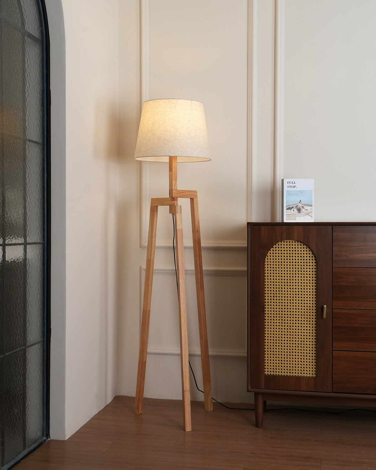 Lámpara de pie trípode de madera Tresalba – encendida en la esquina de un salón