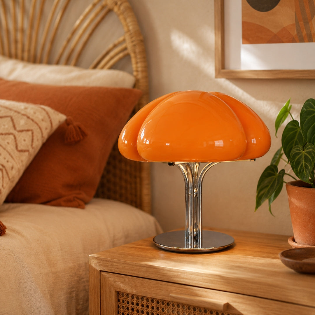 Lámpara de mesa retro de cristal Trevola – en naranja junto a una cama de ratán
