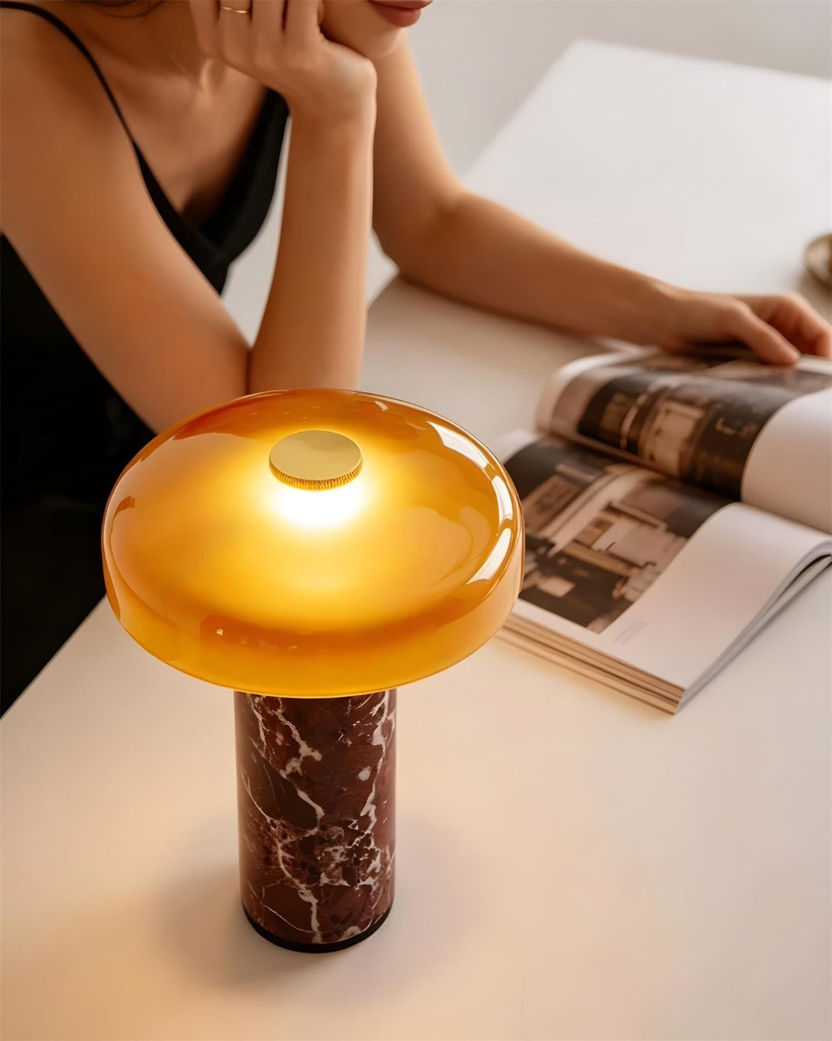 Lámpara de mesa de mármol Trufela – encendida junto a una revista