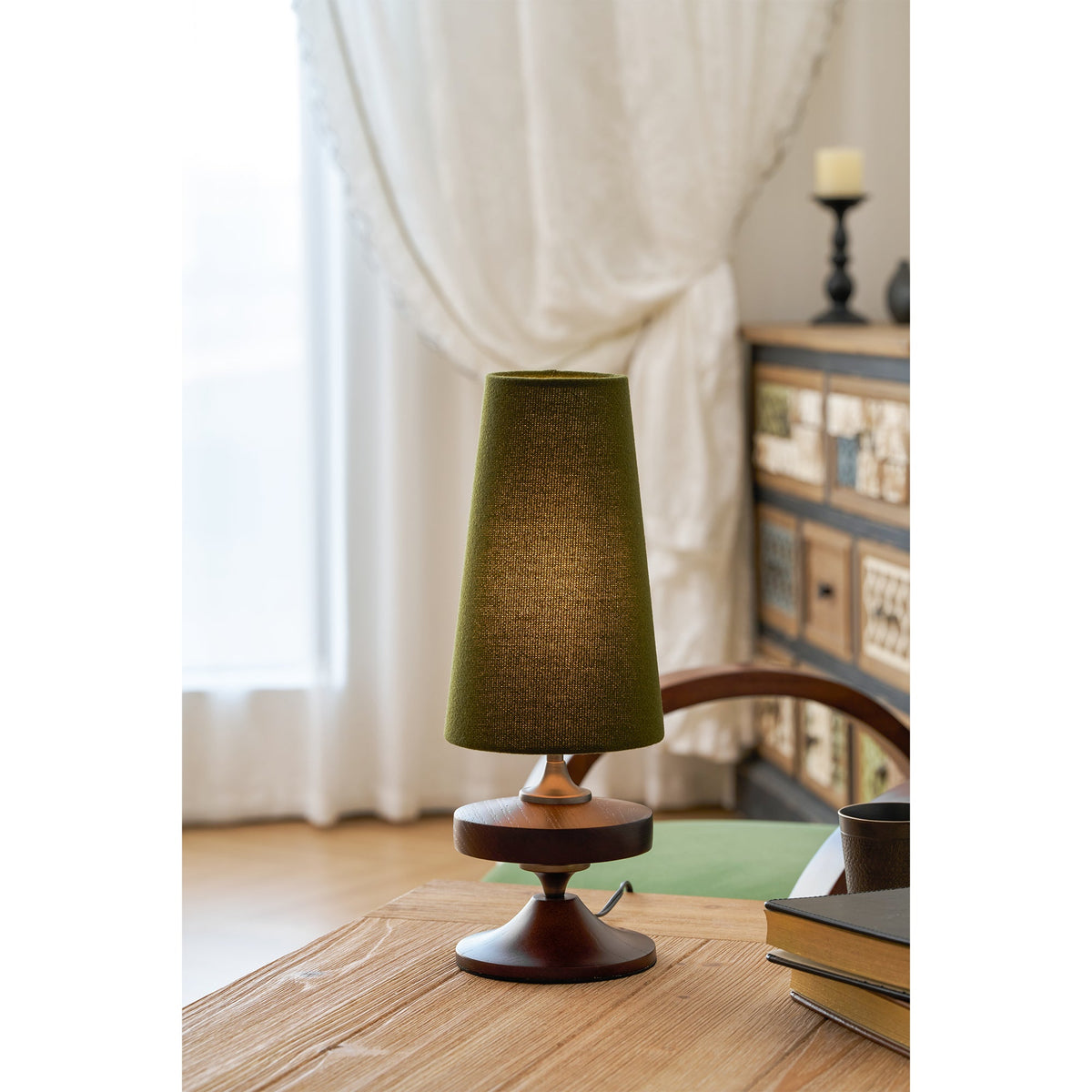 Lámpara de mesa de madera torneada Tulvia – con pantalla verde sobre una mesa de madera