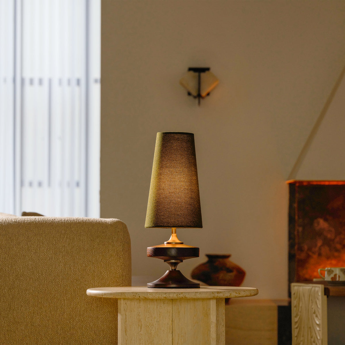 Lámpara de mesa de madera torneada Tulvia – encendida con pantalla verde en un salón