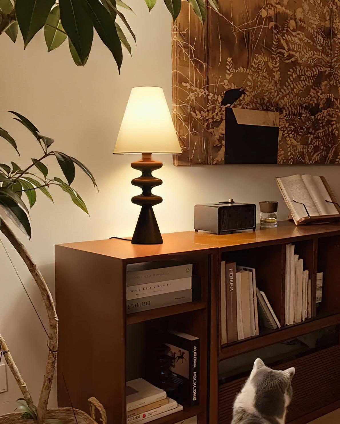 Lámpara de mesa de madera Undora – en negro sobre una estantería