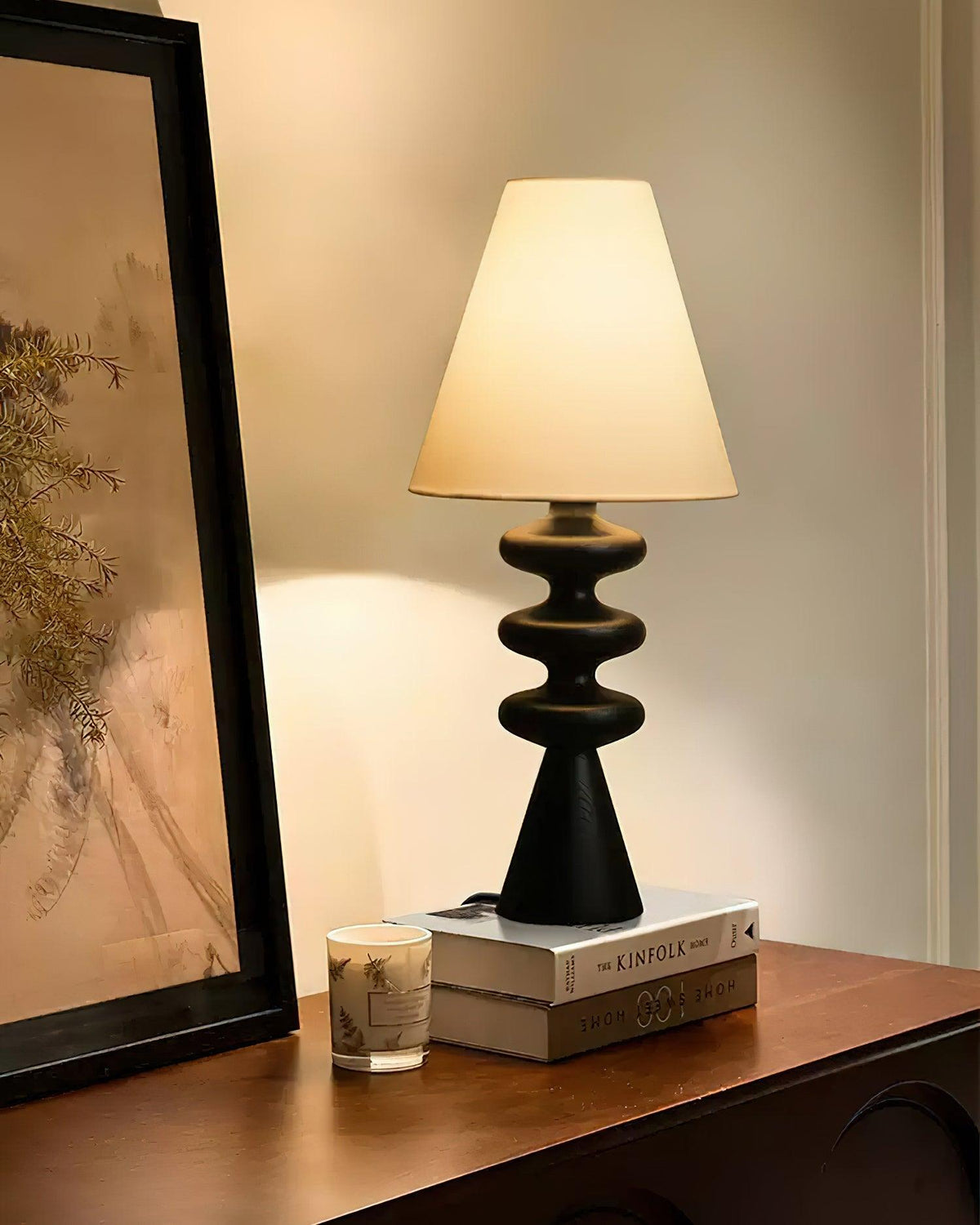 Lámpara de mesa de madera Undora – en negro junto a un cuadro
