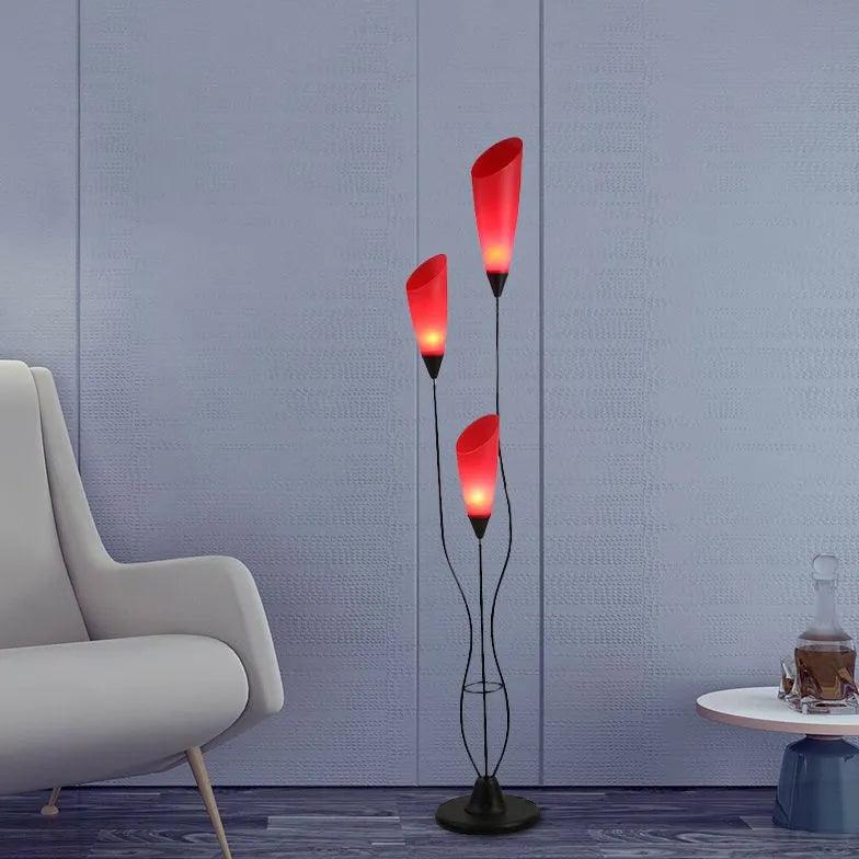 Lámpara de pie de tres pétalos rojos Jacinta – junto a un sillón gris y una mesa auxiliar