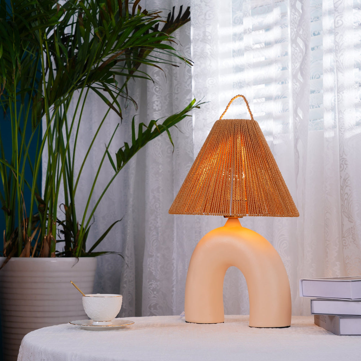 Lámpara de mesa de cerámica Velarca – en beige junto a una planta