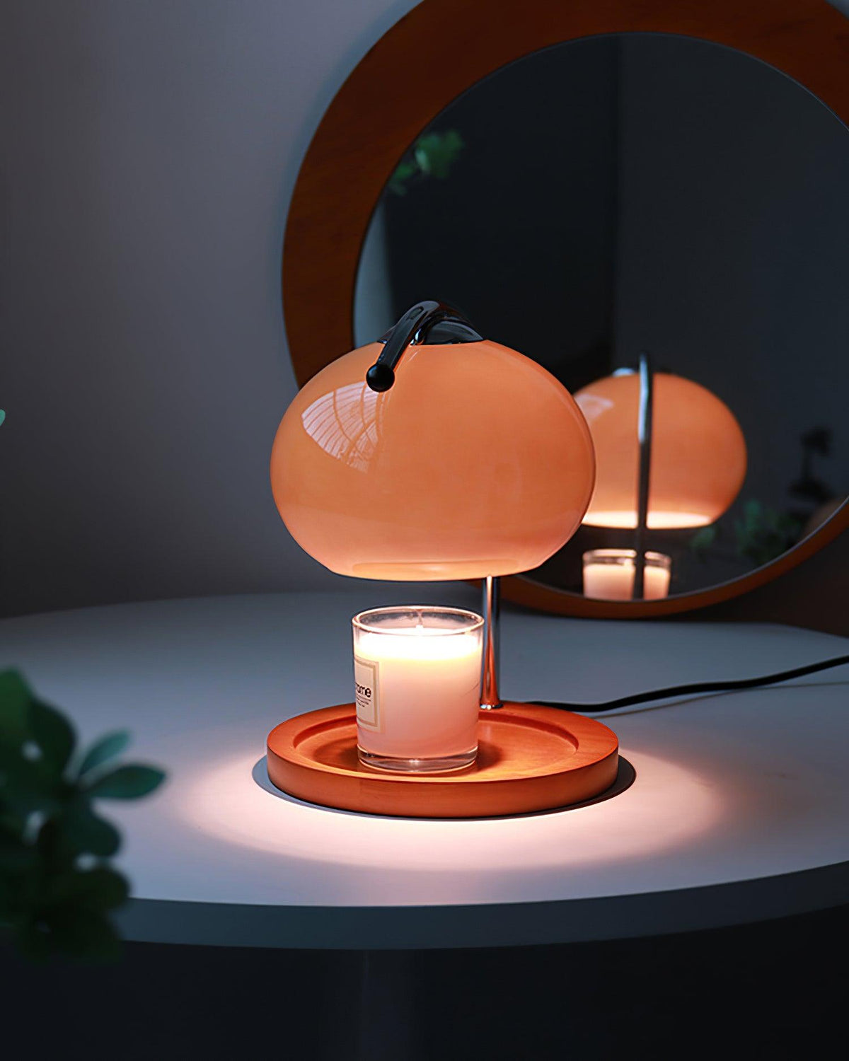 Lámpara calentador de velas Velunda – en color marrón encendida con la vela junto a un espejo