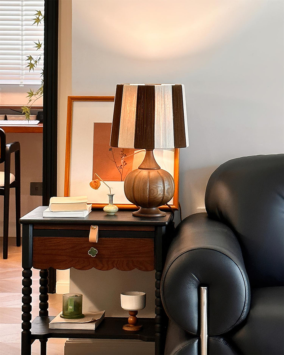 Lámpara de mesa de madera a rayas Vetora – en nogal junto a un sillón de cuero