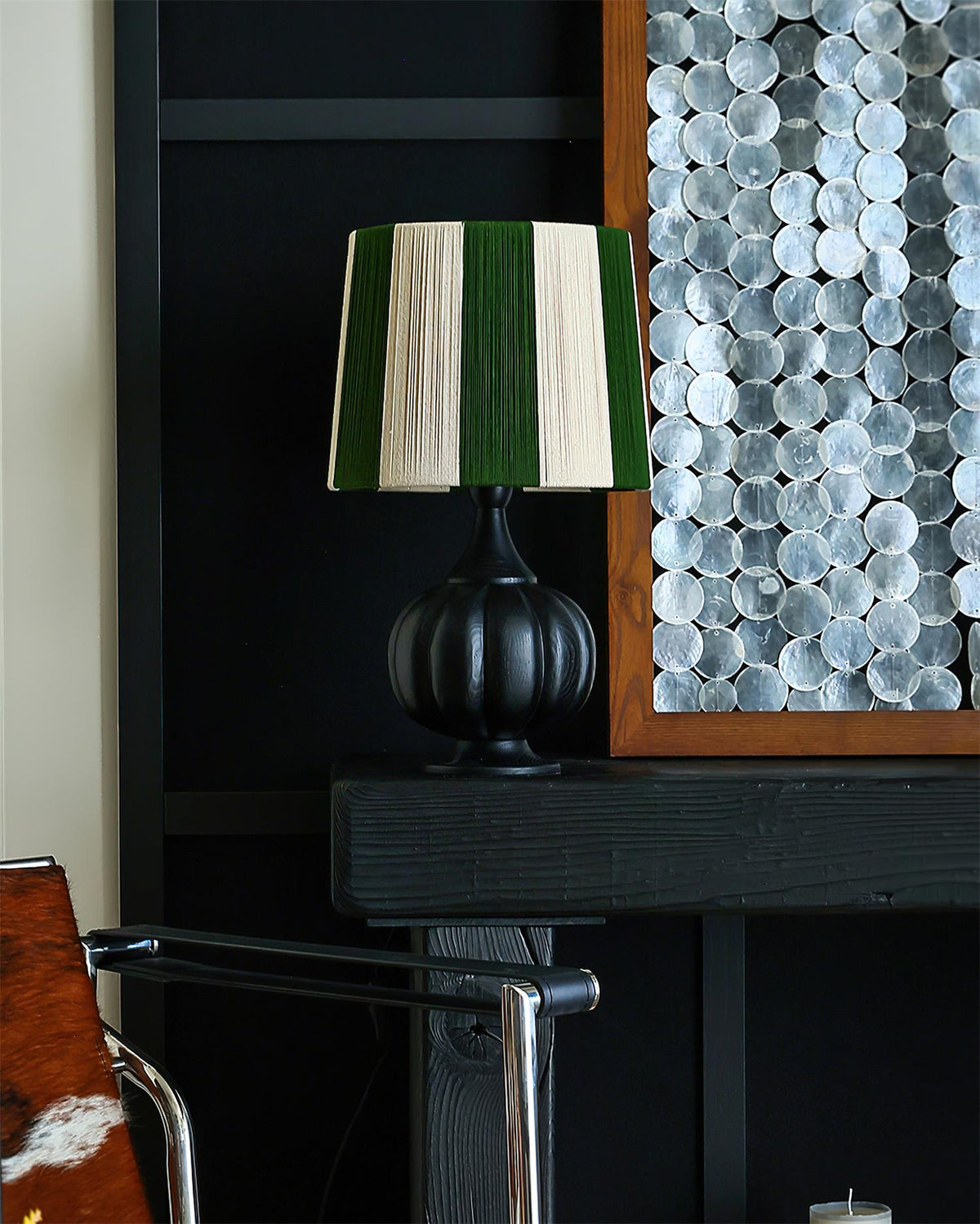 Lámpara de mesa de madera a rayas Vetora – en negro junto a un panel decorativo