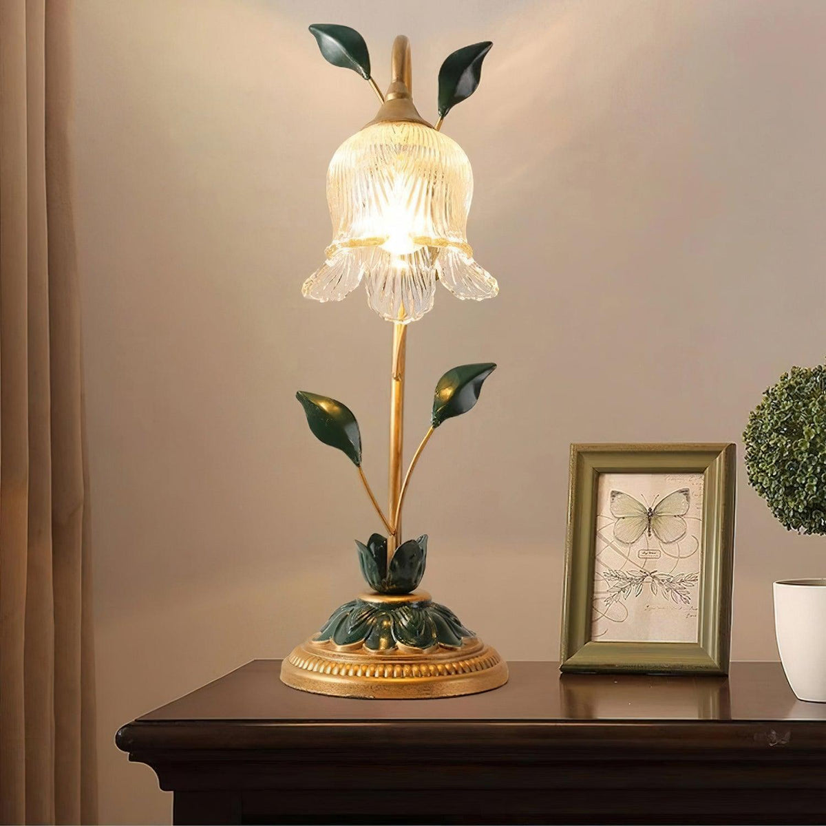 Lámpara de mesa floral Vinela – encendida sobre una mesita