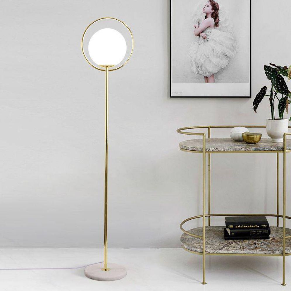Lámpara de pie globo de cristal con aro dorado Soluna – junto a un carrito dorado