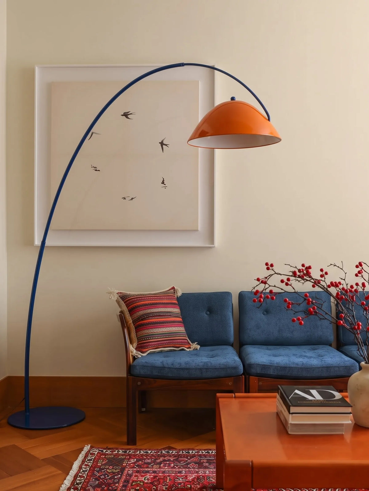 Lámpara de pie arco Vorcela de metal – pantalla naranja junto a un sofá azul