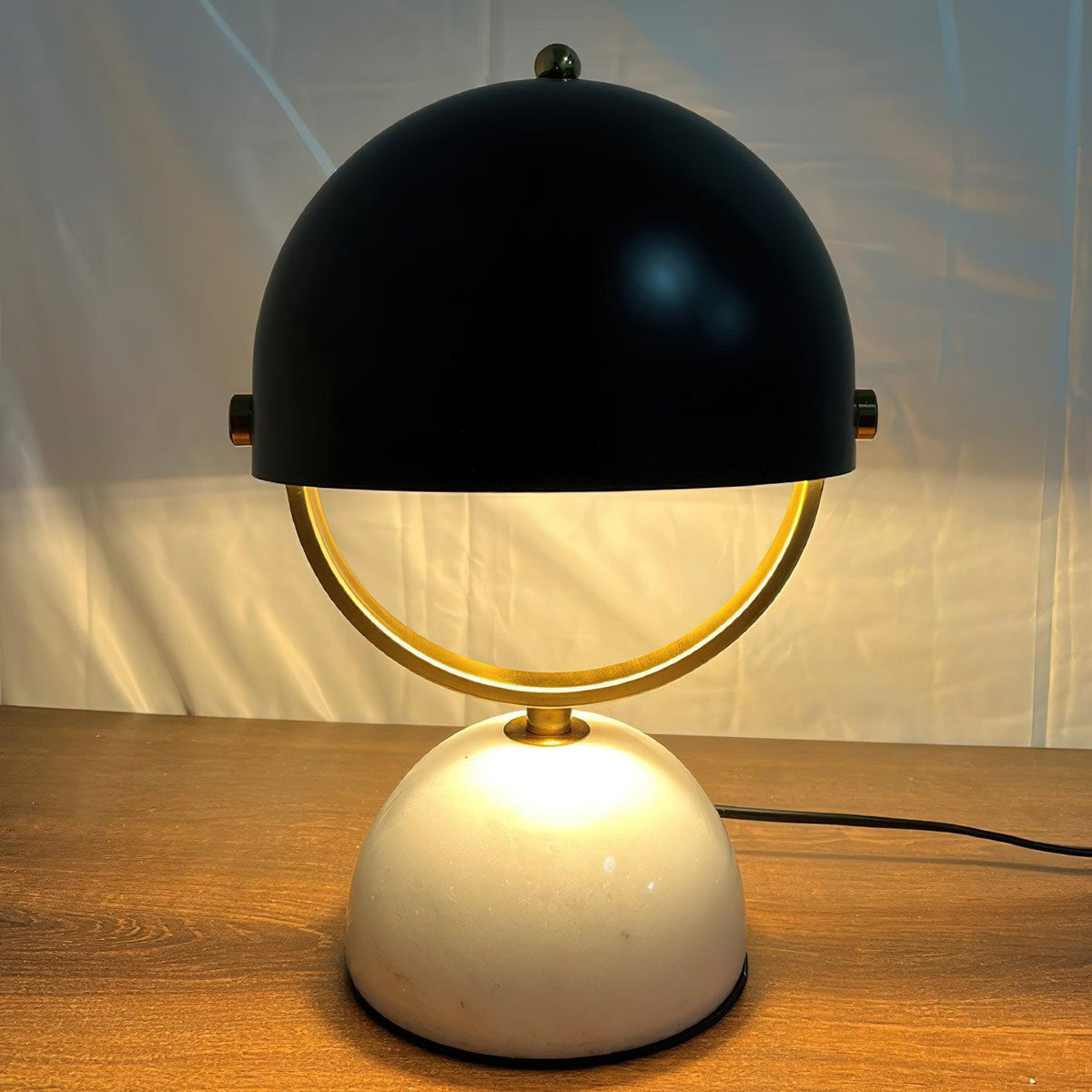 Lámpara de mesa de mármol Yelma – encendida sobre una mesa de madera