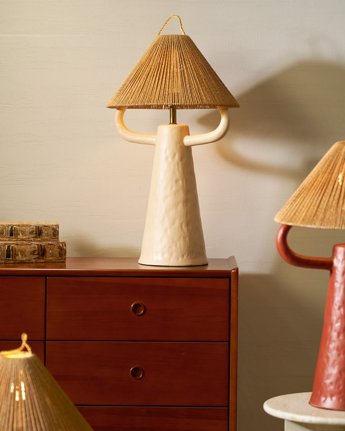 Lámpara de mesa de cerámica Yutela – en beige junto a una cómoda