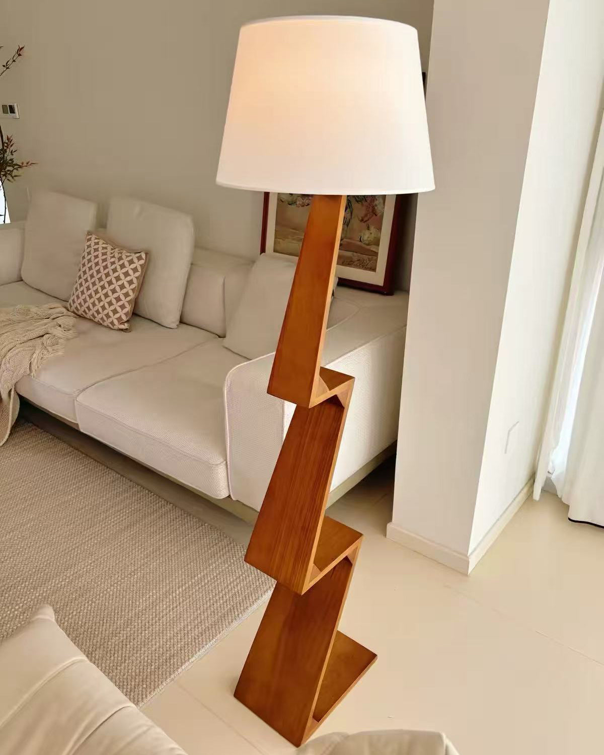 Lámpara de pie de madera en zigzag Zagora – junto a un sofá blanco