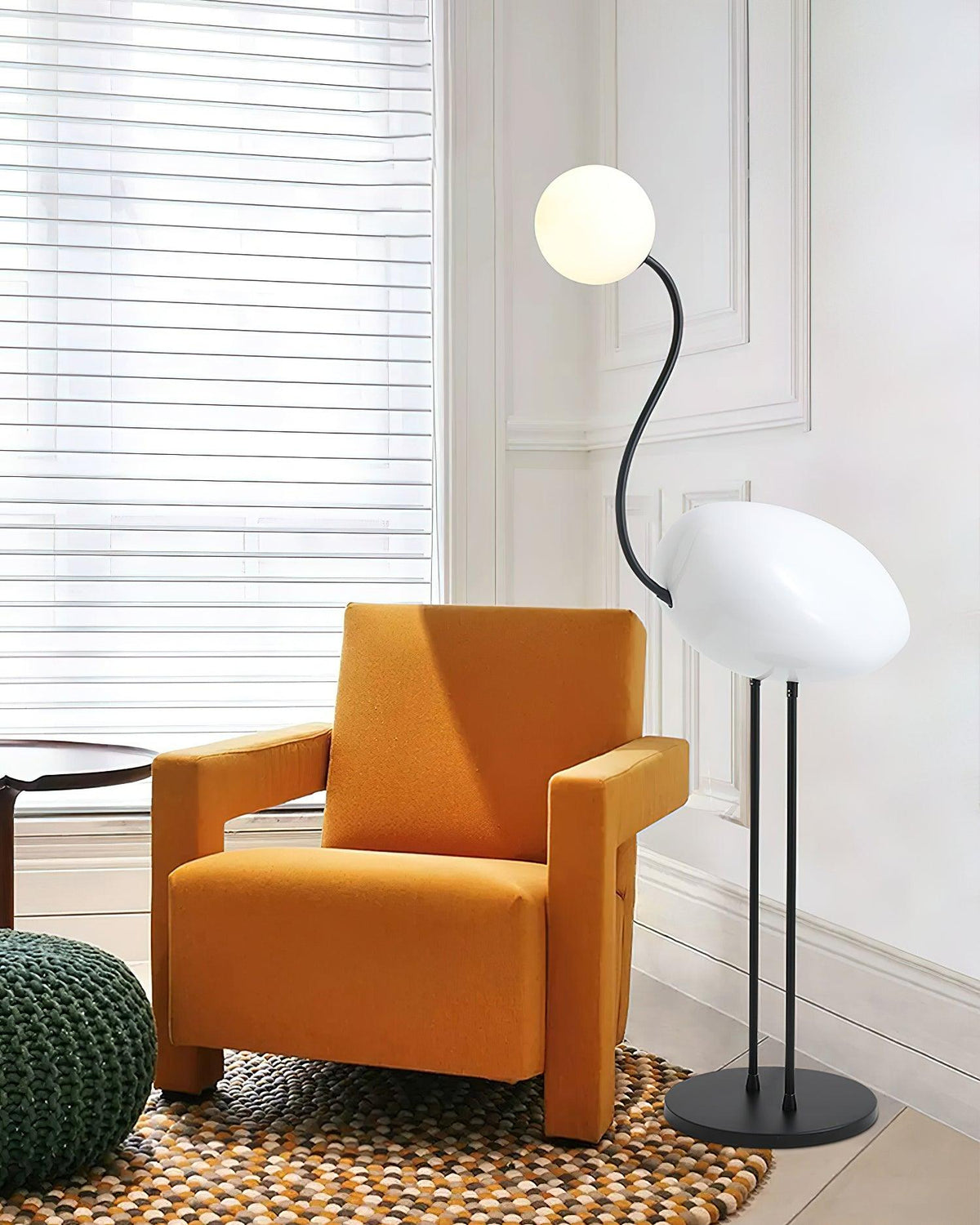 Lámpara de pie pájaro Zancalia – blanca junto a un sillón naranja