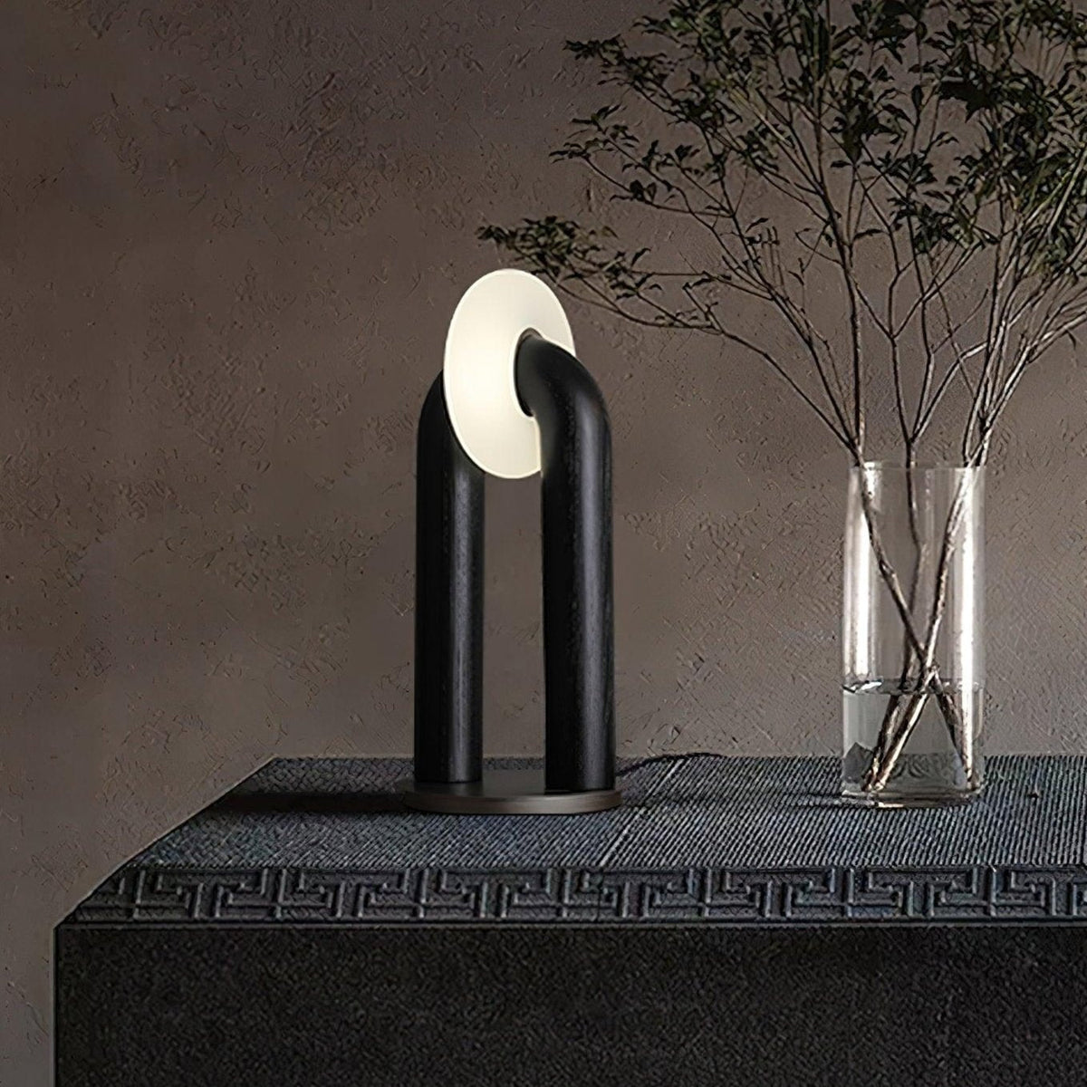Lámpara de mesa de madera Zevelo – en negro junto a un jarrón