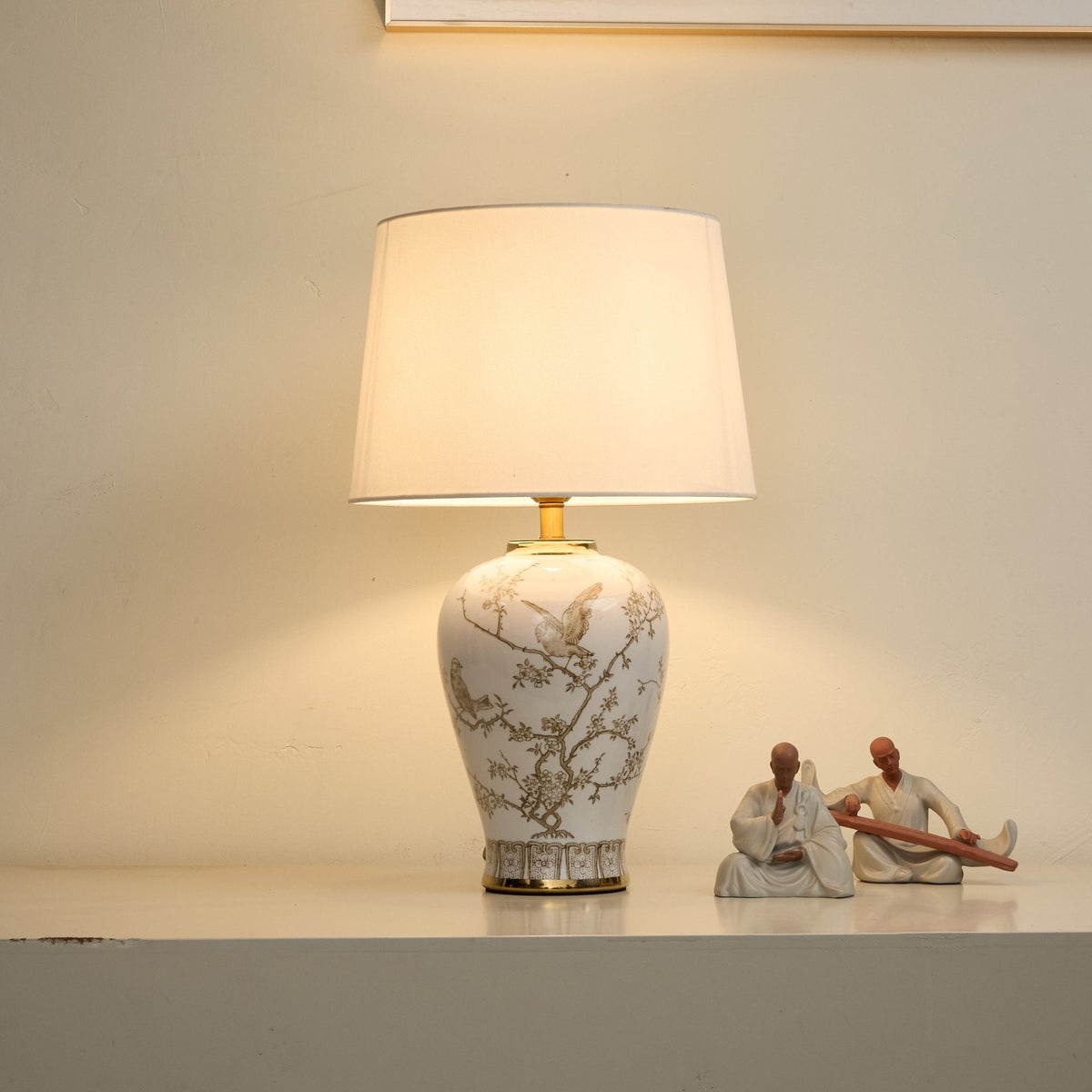 Lámpara de mesa de cerámica Zorzela – encendida con luz cálida junto a unas figuras